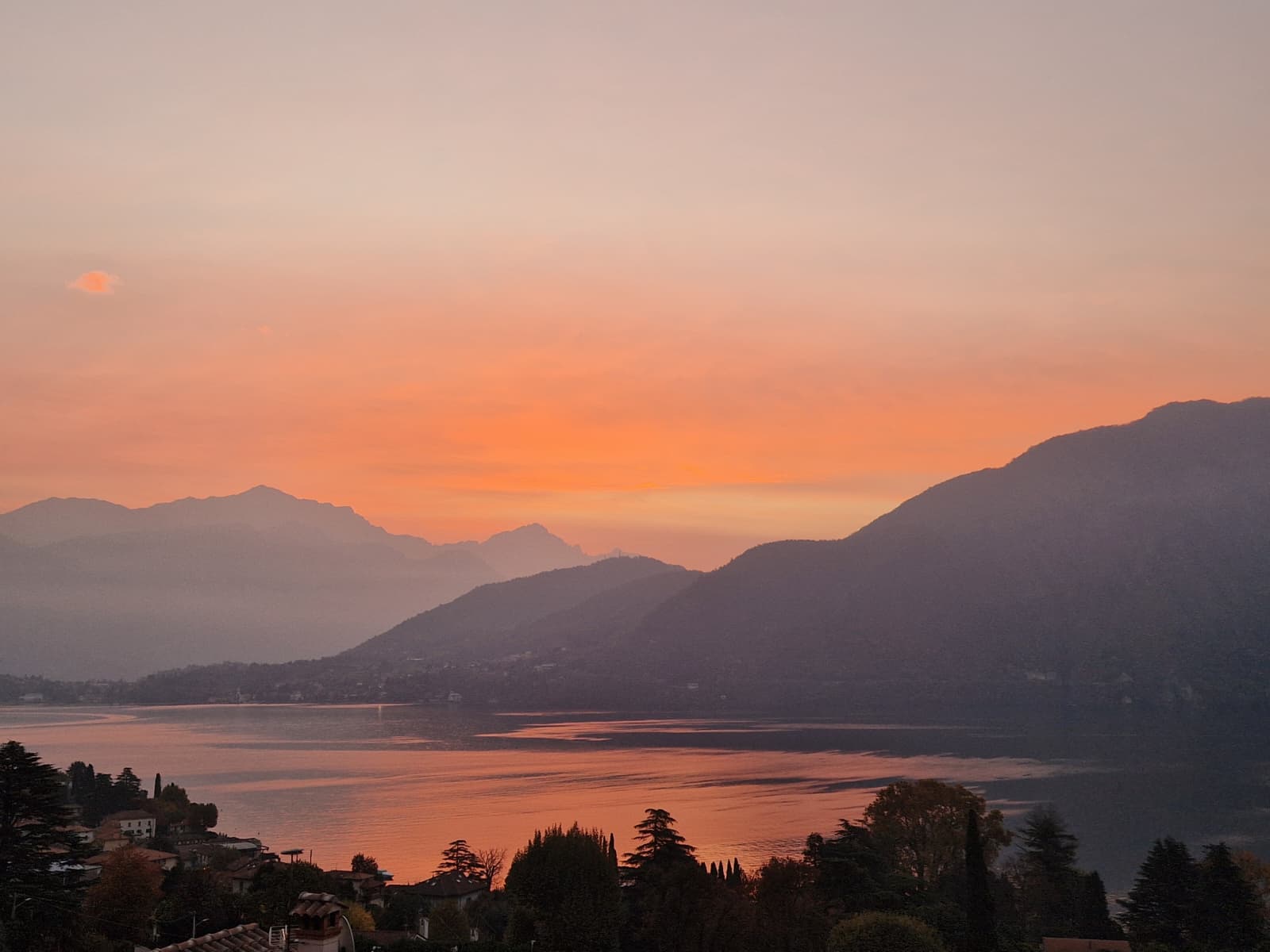 Alba sul Lago di Como dalla Tremezzina, con luce dorata riflessa sull'acqua e le montagne sullo sfondo.