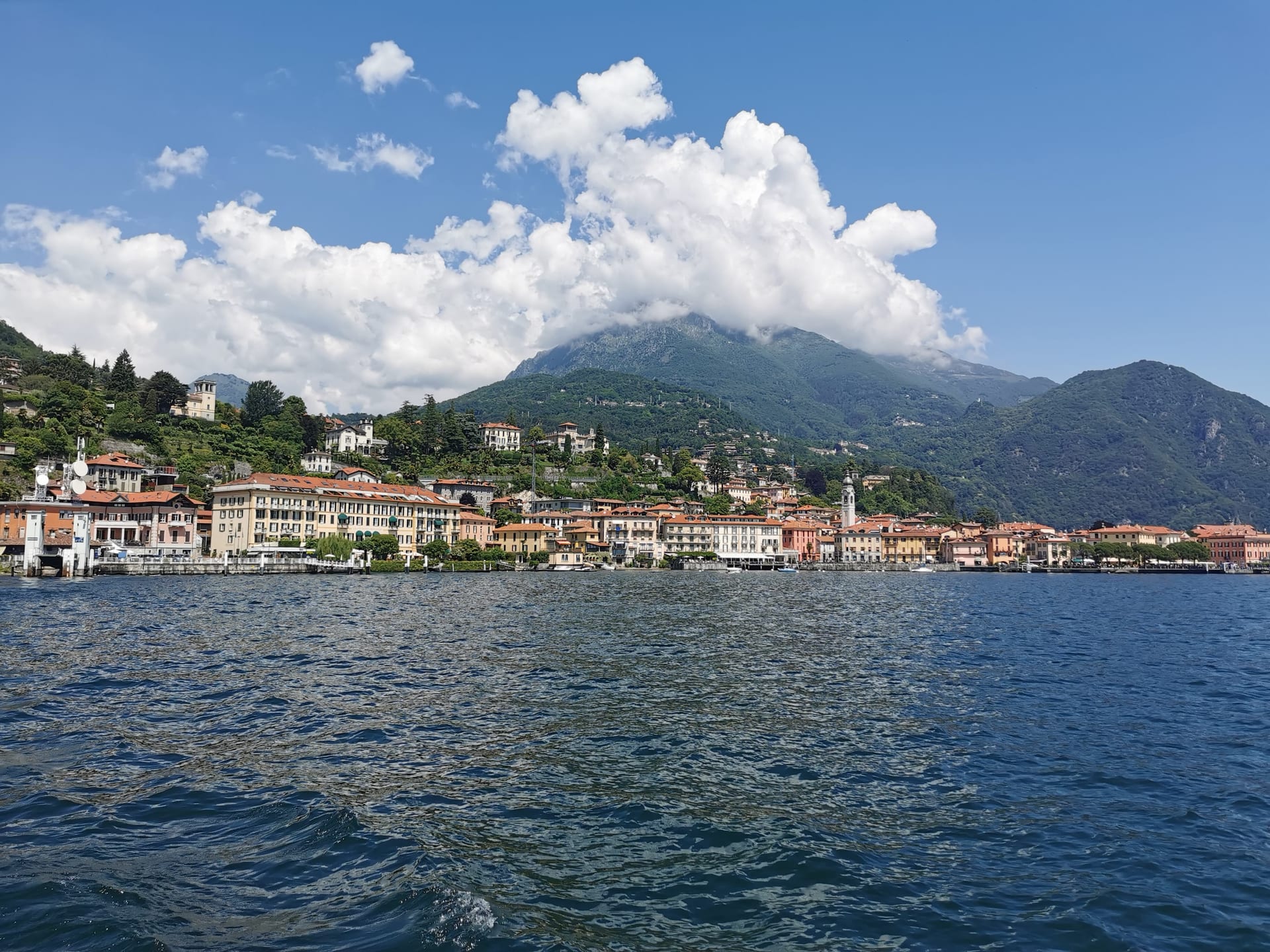 Vista di Varenna sul Lago di Como con le case colorate lungo la riva e le montagne sullo sfondo.