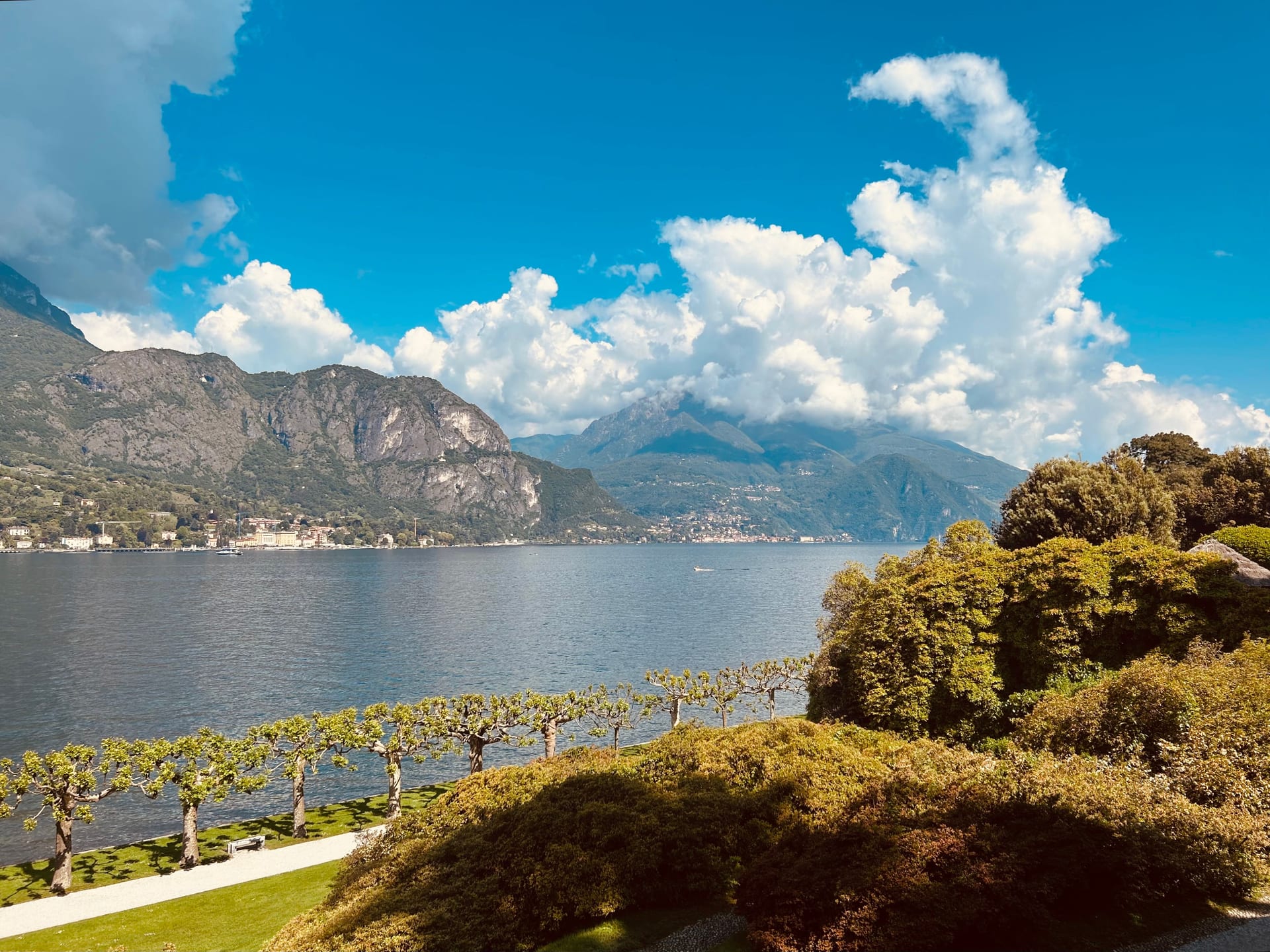 Terrazza di un giardino sul Lago di Como, con platani potati lungo la riva e le montagne sullo sfondo